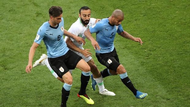 Gelandang Arab Saudi Abdullah Otayf mendapat kawalan dari dua pemain Uruguay.