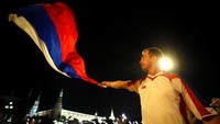 Seorang suporter mengibarkan bendera setelah tim nasional Rusia berhasil menundukkan Mesir. Maxim Shemetov/Reuters.