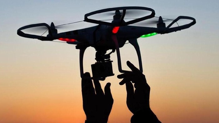 Flying drone with camera on the sky at sunset