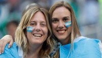 Dua suporter Argentina pamerkan senyum cantik rayakan kemenangan Messi cs. Toru Hanai/Reuters.
