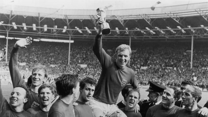 timnas inggris piala dunia 1966 bobby moore England captain Bobby Moore (1941 - 1993) holds up the Jules Rimet trophy as he is carried on the shoulders of his team-mates after their 4-2 victory over West Germany in the World Cup Final at Wembley Stadium. Also pictured are (left-right) Nobby Stiles, Jack Charlton, Alan Ball, Martin Peters, Geoff Hurst, Ray Wilson, George Cohen and Bobby Charlton. (Photo by Central Press/Getty Images)