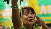 Suporter wanita ini ikut merayakan kemenangan Brasil di Rie de Janeiro sambil membawa seekor ayam. REUTERS/Sergio Moraes.