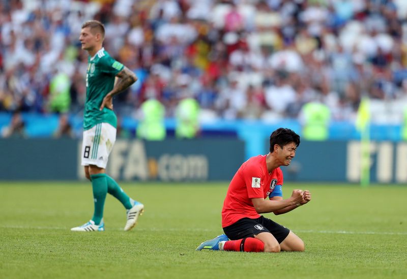 South Korea vs Germany KAZAN, RUSSIA - JUNE 27: Son Heung-Min of Korea Republic sinks to his knees as he celebrates following his sides victory, as a dejected Toni Kroos of Germany can be seen walking off after the 2018 FIFA World Cup Russia group F match between Korea Republic and Germany at Kazan Arena on June 27, 2018 in Kazan, Russia. (Photo by Catherine Ivill/Getty Images)