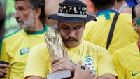 Tak mampu memeluk trofi Piala Dunia yang asli, biarlah suporter ini memeluk trofi Piala Dunia yang dibawanya. Toru Hanai/Reuters.