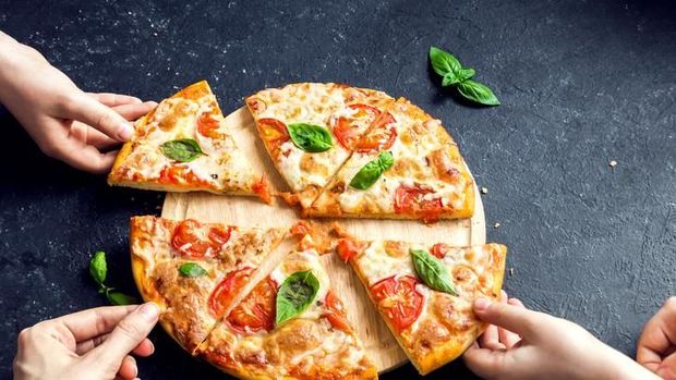 Preparing Classical Pizza Margherita. Cooks add grated parmesan cheese. Selective focus