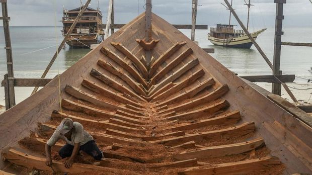 This picture taken on July 7, 2018 shows a shipbuilder working on a traditional Pinisi boat in Tana Beru, on Indonesia's South Sulawesi island.The iconic schooners, known as Pinisi, have given builders on Sulawesi island -- the heart of the industry -- their reputation as master craftsmen and some of the best sailors around. / AFP PHOTO / YUSUF WAHIL