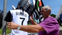 Seorang penjaja terlihat sedang merapikan jersey Ronaldo yang menjadi salah satu barang utama dagangannya. (Foto: Massimo Pinca/Reuters)