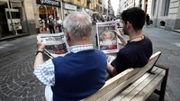 Dua warga beda generasi di kota Turin tampak sedang asyik menyimak kabar megatransfer Ronaldo dari Real Madrid ke Juventus. (Foto: Isabella Bonotto/AFP)