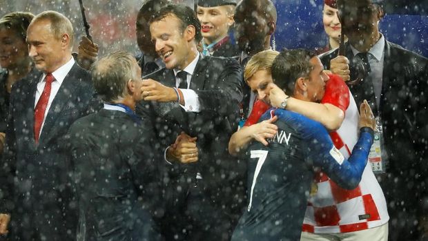 DI baah guyuran hujan, Macron memeluk pelatih timnas Didier Deschamps atas gelar juara dunia.