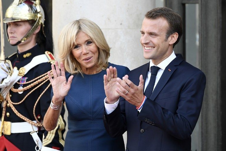 French president Emmanuel Macron holding the trophy (C) and his wife Brigitte Macron (C-L), France's coach Didier Deschamps (5thR), France's goalkeeper Hugo Lloris (6thR) pose for a family photo  at a reception for the French national football team after they won the Russia 2018 World Cup final football match at the Elysee Presidential Palace on July 16, 2018 in Paris. France celebrated their second World Cup win 20 years after their maiden triumph on July 15, 2018, overcoming a passionate Croatia side 4-2 in one of the most gripping finals in recent history. / AFP PHOTO / Lionel BONAVENTURE