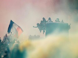 Banyak di antara warga Paris yang menyalakan flare untuk merayakan kepulangan tim nasional mereka. Foto: Charles Platiau/Reuters