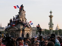 Saking sesaknya jalanan di Paris, sebagian warga sampai memanjat bangunan untuk menyaksikan parade ini. Foto: Jean-Paul Pelissier/Reuters