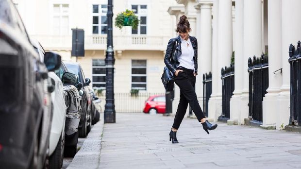 Fashion portrait of beautiful woman dancing in the city street in London. Autumn season.