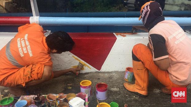Petugas PPSU mengecat jembatan dan tembok trotoar dengan corak Asian Games 2018, di Paseban, Jakarta.