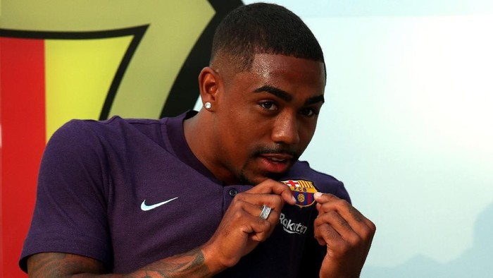 Brazilian soccer player Malcom Filipe Silva de Oliveira poses in front of a FC Barcelona logo at their offices next to Camp Nou stadium in Barcelona, Spain July 24, 2018. REUTERS/Albert Gea