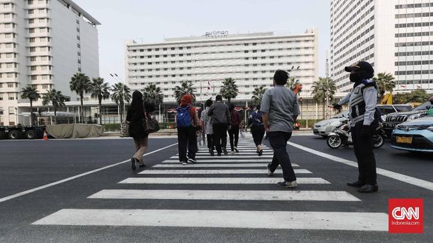 Pejalan kaki memanfaatkan pelican crossing di Kawasan Bundaran HI, Jakarta, Senin, 30 Juli 2018. Jembatan penyeberangan orang di kawasan Bundara Hotel Indonesia, Jakarta Pusat hari ini ditutup sehingga tak bisa dipakai lagi. Sebagai gantinya, pejalan kaki bisa menggunakan pelican crossing yang sudah dibuat sebagai tempat penyeberangan sementara. CNNIndonesia/Safir Makki