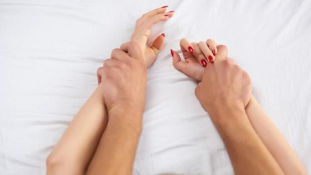 Hands of couple in bed. Man and woman making love.
