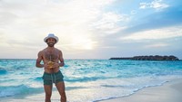 Mohamed Salah tampak memegang kelapa yang diminumnya sambil menikmati hamparan pasir dan deburan ombak. (Instagram @MoSalah11)