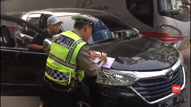 Petugas melakukan penilangan terhadap pelanggar ganjil genap.