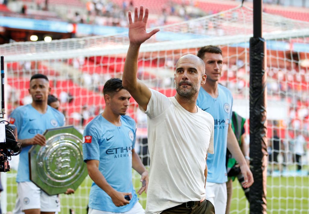Soccer Football - FA Community Shield - Manchester City v Chelsea - Wembley Stadium, London, Britain - August 5, 2018  Manchester City manager Pep Guardiola celebrates by waving to the fans, as Gabriel Jesus holds the trophy after the match  Action Images via Reuters/Craig Brough