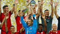 Manuel Neuer mengangkat trofi pertama Bayern Munich di musim ini. Reuters/Ralph Orlowski.
