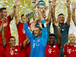 Manuel Neuer mengangkat trofi pertama Bayern Munich di musim ini. Reuters/Ralph Orlowski.