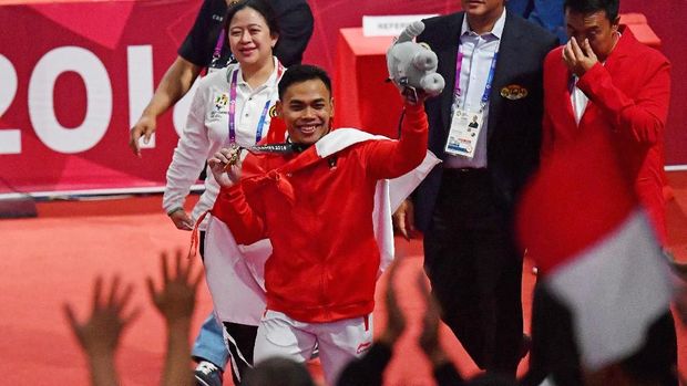 Menko PMK Puan Maharani (kiri) dan Menpora Imam Nahrawi (kanan) mendampingi lifter Indonesia Eko Yuli Irawan menyapa penonton usai nomor angkat besi putra 62 kg Group A Asian Games ke-18 2018 di JiExpo Jakarta, Senin (20/8). Eko berhasil meraih emas pada nomor tersebut. ANTARA FOTO/INASGOC/Fanny Octavianus/YU/18.
