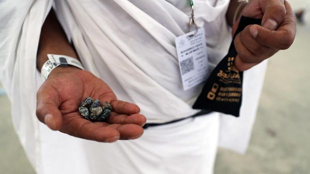 A Muslim pilgrim holds stones as he partakes in the symbolic stoning of the devil at the Jamarat Bridge in Mina, near Mecca, which marks the final major rite of the Hajj on on August 21, 2018. Muslims from across the world are gathering in Mecca in Saudi Arabia for the annual Hajj pilgrimage, one of the five pillars of Islam. / AFP PHOTO / AHMAD AL-RUBAYE