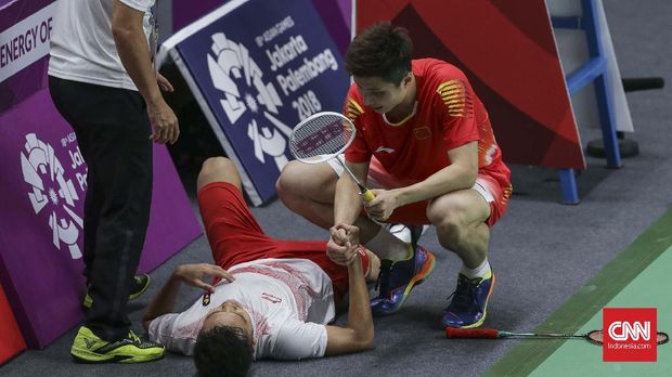 Pebulu tangkis tunggal putra Cina Shi Yuqi (kanan) menghampiri pebulu tangkis tunggal putra Indonesia Anthony Sinisuka Ginting (tengah) yang mengalami cedera saat set ketiga pada babak final beregu putra Asian Games 2018 di Istora Senayan, Jakarta, Rabu (22/8). Tim bulutungkis beregu putra Indonesia akhirnya kalah 1-3 atas Tim bulutungkis beregu putra Cina