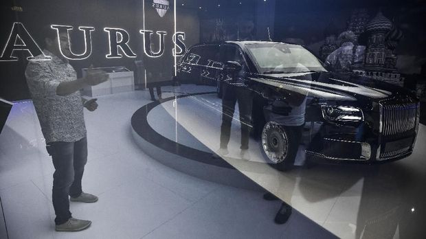 A visitor looks at Russian President Vladimir Putin's new Aurus Senat limousine through a panel of semi-transparent glassat the Moscow International Motor Show in Moscow on August 29, 2018.A Russian state automobile research centre NAMI presented the two versions of luxury class Aurus Senat limousine and Aurus Senat sedan at the motor show, as Russia launched a homegrown luxury car marque that includes a limousine for President Vladimir Putin, with the makers hoping to lure away super-wealthy customers from brands such as Rolls-Royce. / AFP PHOTO / Alexander NEMENOV
