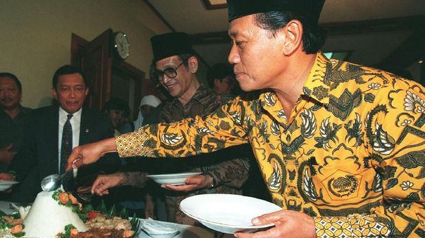 Chairman of the ruling Golkar party Harmoko (R), along with his counterpart from the United Development Party Ismail Hasan Metareum (C) help themselves to a traditional rice cone (tumpeng) during a Syukuran (traditional thanksgiving ceremony) at the National Elections Institute 24 June, as Home Affairs Minister Yogie S. Memed (L) looks on.  Harmoko celebrated his party's overwhelming win in last month's parliamentary elections.  Golkar grabbed a record 325 seats in the Indonesian parliament / AFP PHOTO / JOHN MACDOUGALL