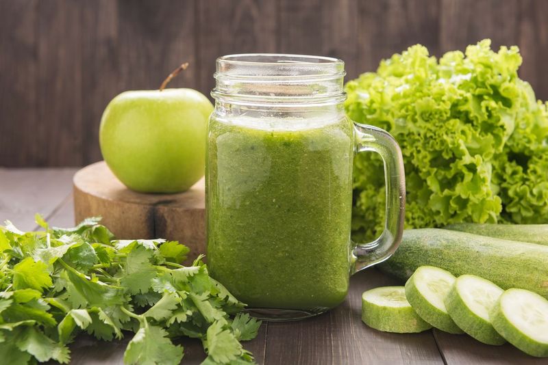 Healthy green vegetables and green fruit smoothie on rustic wood table.