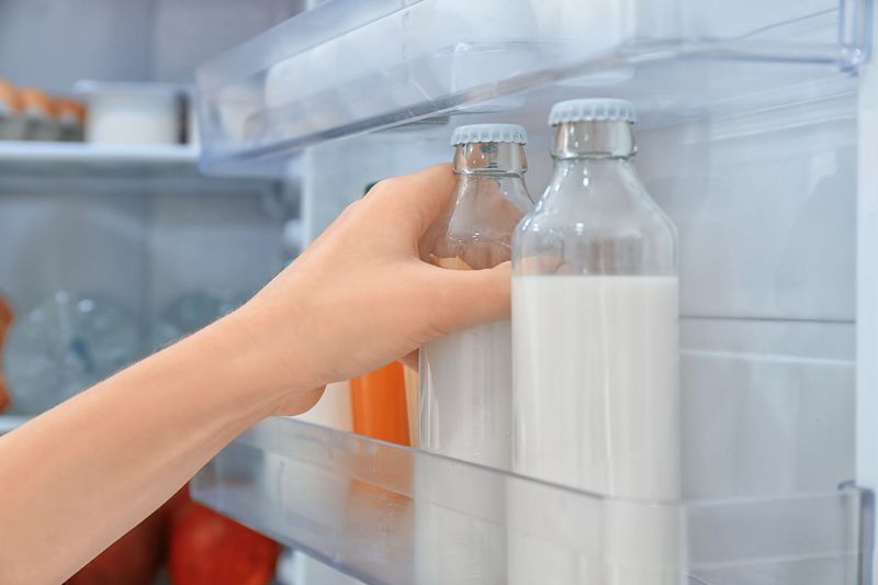 Closeup shot of a glass of milk on a dairy farm with cattle grazing in the background