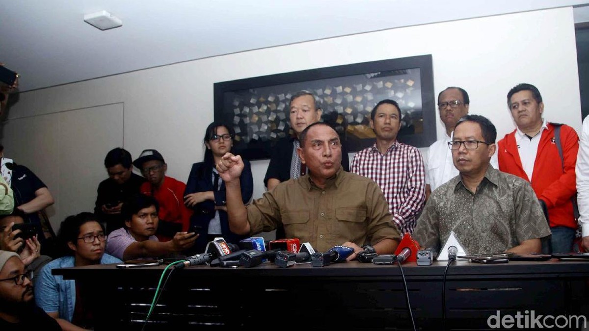 Anggota exco PSSI Johar Lin Eng (baju hitam) berdiri di belakang Ketum PSSI Edy Rahmayadi saat mengumumkan penghentian Liga 1 beberapa waktu lalu. (Pradita Utama/detikSport)
