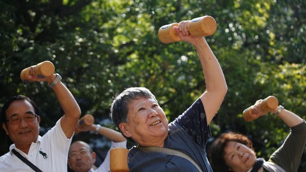 Elderly and middle-aged people exercise with wooden dumbbells during a health promotion event to mark Japans 