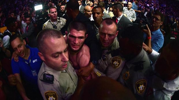 Aksi Khabib Nurmagomedov memanjat keluar pagar oktagon usai mengalahkan Conor McGregor memicu kerusuhan di T-Mobile Arena. (