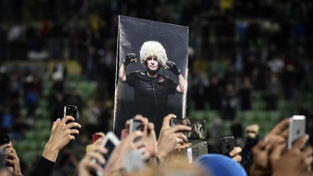 Fans hold a picture of UFC lightweight champion Khabib Nurmagomedov of Russia during a meeting upon the arrival at the Anzhi-arena stadium in Makhachkala on October 8, 2018. He defeated Conor McGregor of Ireland in their UFC lightweight championship bout by way of submission during the UFC 229 event inside T-Mobile Arena on October 6, 2018 in Las Vegas, Nevada / AFP PHOTO / Vasily MAXIMOV