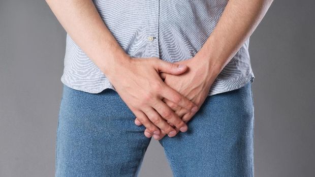 Pain in prostate, man suffering from prostatitis or from a venereal disease, studio shot on gray background