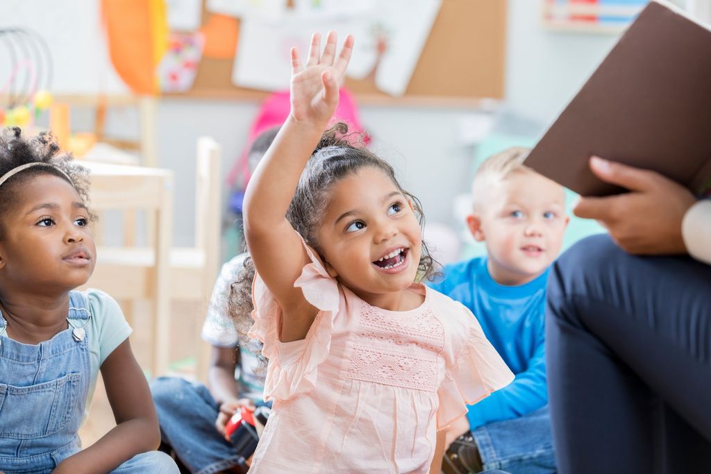 Happy female teacher teaching group of small kids in a preschool.