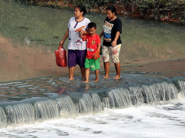 Potret Warga Nekat Sebrangi Kanal Banjir Timur