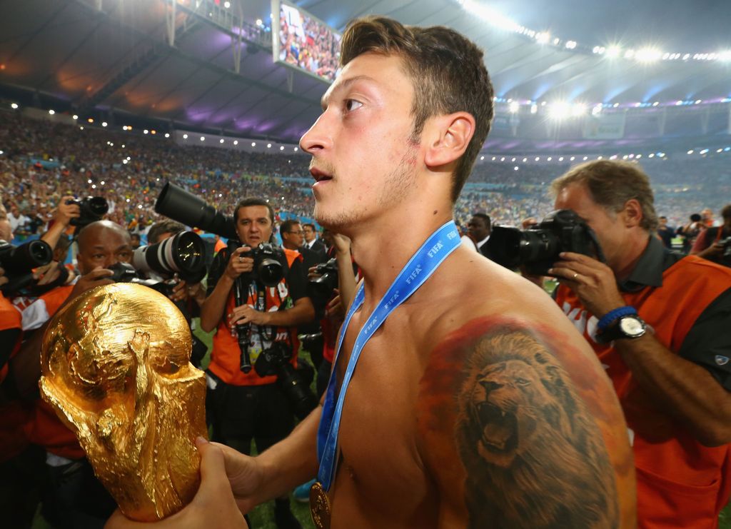 RIO DE JANEIRO, BRAZIL - JULY 13: Mesut Oezil  of Germany celebrates with the World Cup trophy  after defeating Argentina 1-0 in extra time during the 2014 FIFA World Cup Brazil Final match between Germany and Argentina at Maracana on July 13, 2014 in Rio de Janeiro, Brazil.  (Photo by Martin Rose/Getty Images)