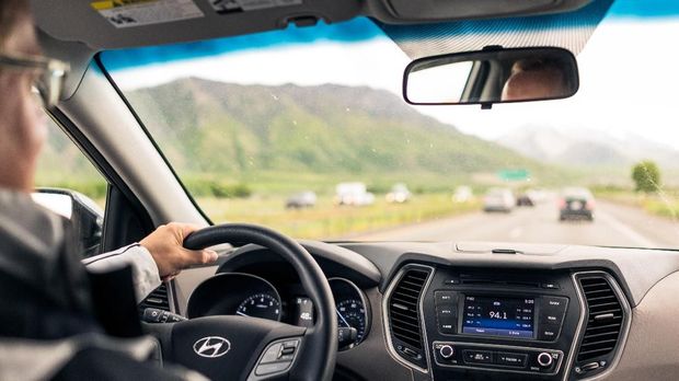 Utah, USA - A view of a man driving a Hyundai SUV on a rural freeway, with light daytime traffic on the road ahead.