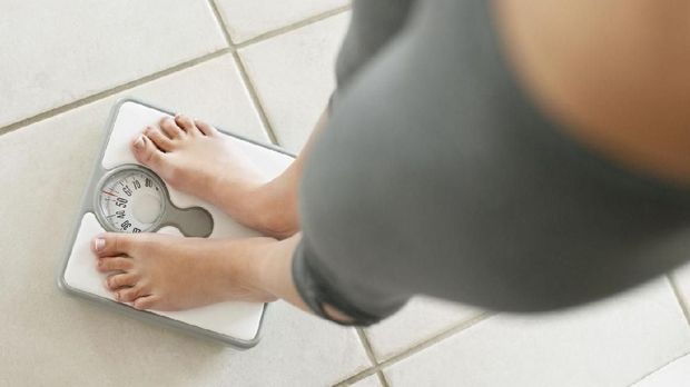 Weighloss- Low section of a young on a weighing scale