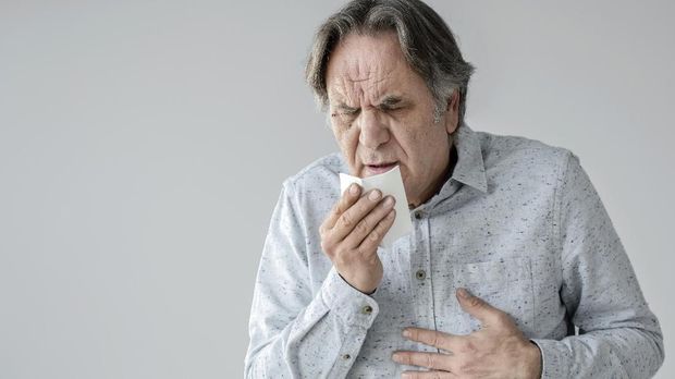 Old man coughing to tissue