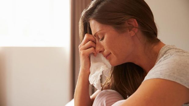 Woman Suffering From Depression Sitting On Bed And Crying