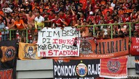 Spanduk-spanduk The Jakmania dibentangkan di pagar pembatas tribun stadion.