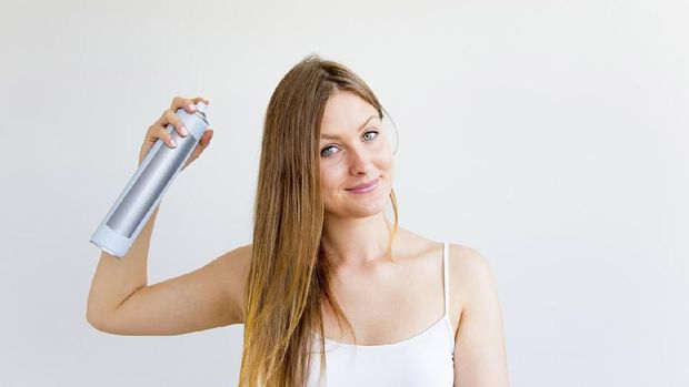 A portrait of a woman styling and drying her hair