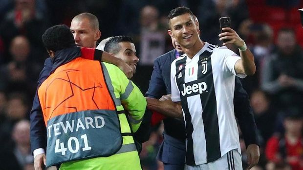 Cristiano Ronaldo menyempatkan diri berfoto dengan fan yang menerobos masuk ke lapangan Old Trafford.