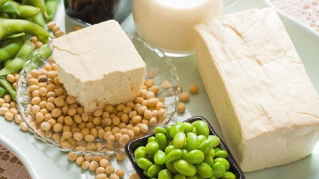 Soy Products. Soy Bean Food and Drink Products Photograph with Several Elements including loose bean,tofu, and soy milk. Full block of tofu.  Half block of tofu sitting on plate of loose soy beans. Green beans in black square bowl. Glass filled with soy milk.