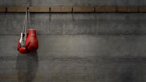 Spotlit boxing gloves hanging on a hanger above an empty wooden bench in a locker change room - 3D render
